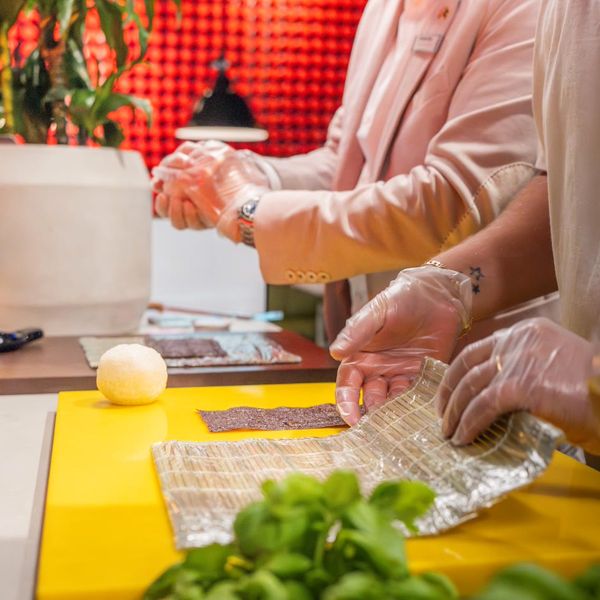 Hände rollen Sushi auf der Bambusmatte