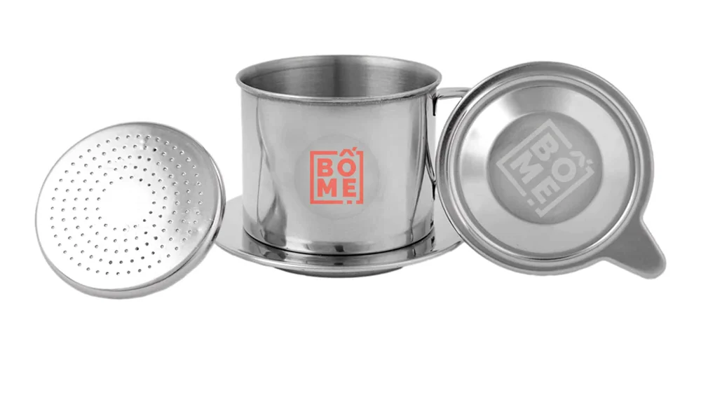 Vietnamesischer Phin-Kaffeefilter aus Edelstahl mit BOME-Gravur, daneben Deckel und Siebeinsatz