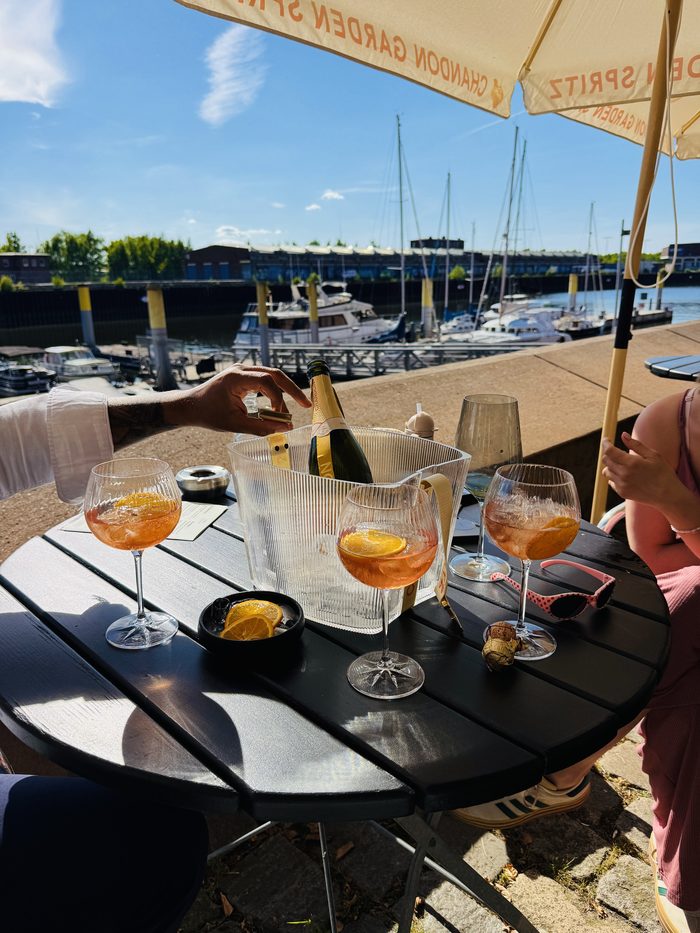 Aperitif-Gläser auf dem Tisch, dahinter die Boote im Hafenbecken