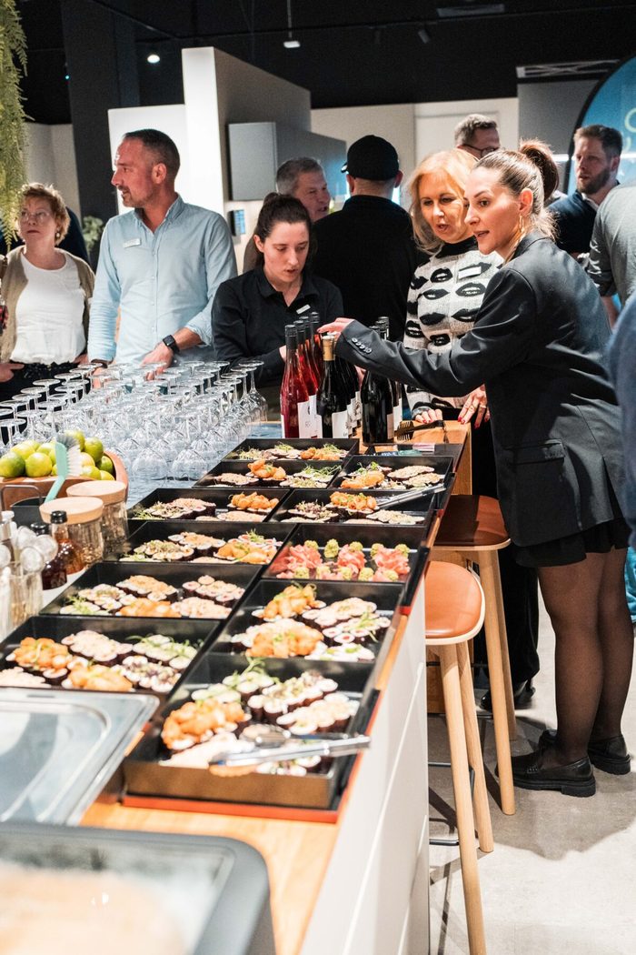 Service reicht Sushi vom Buffet, Gäste stehen am Tresen